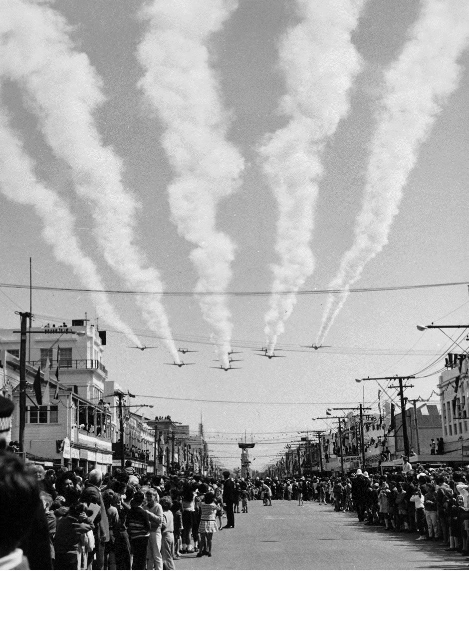 75 Squadron Diamond-Nine flying up Gladstone Road after the flypast at the Civic Ceremony, Gisborne, on Thursday morning 9th October 1969 – Now that is LOW! Note ahead the soon to be encountered Endeavour model sailing ship on a pole, and the clock tower beyond it – photo RNZAF G3-2402